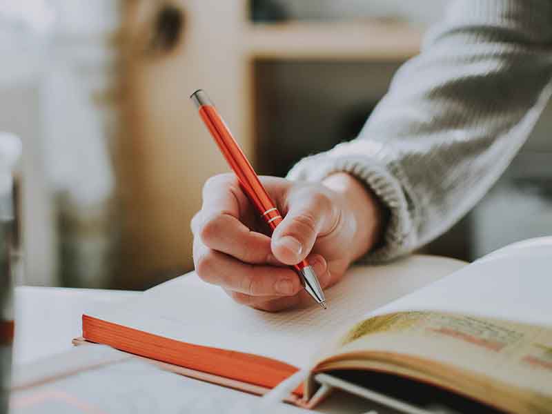 a student is writing something in a notebook