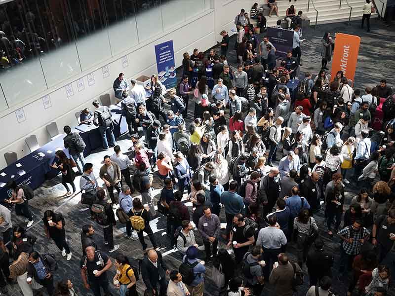 a crowd of people waiting to enter the conference hall in the corridor